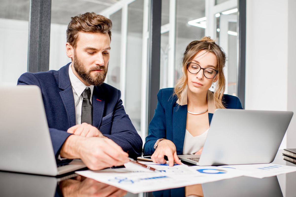 muž a žena vo formálnom oblečení, zamestnanci poisťovne, si prezerajú grafy na papiery