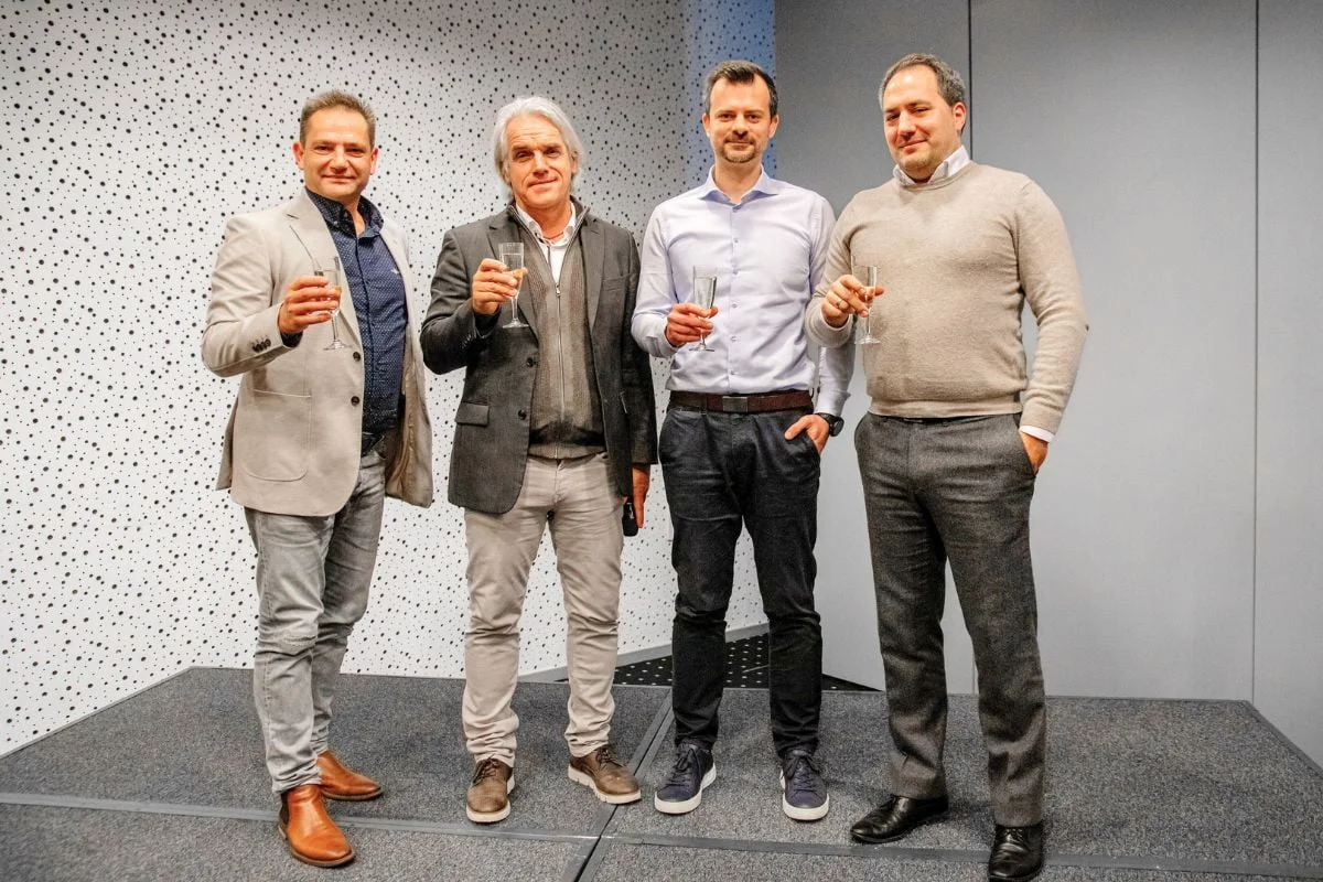 vedenie-msg-life-slovakia-2025 – msg life Slovakia Štyria muži elegantne oblečení stoja spolu a držia šampanské poháre pri firemnom podujatí.